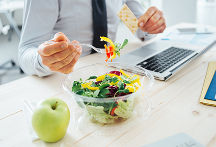 Employee eating healthy salad at desk