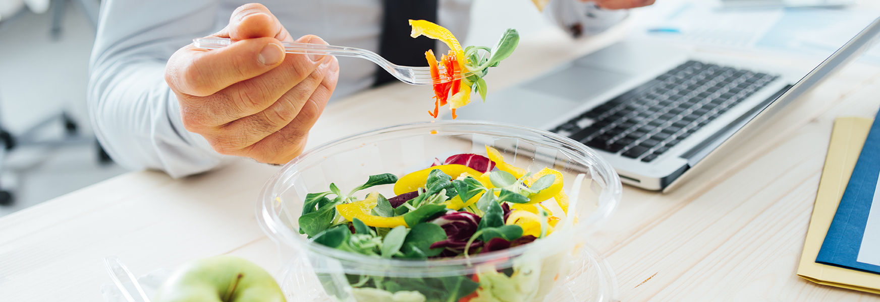 Employee eating healthy salad at desk