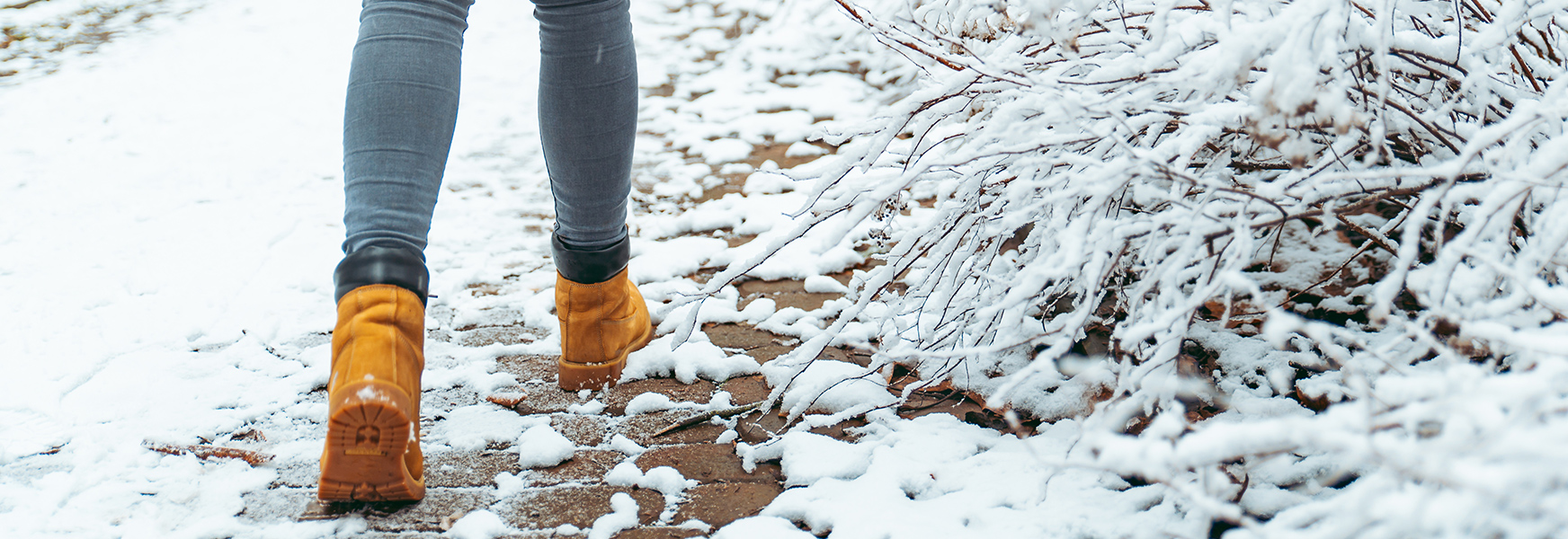 Woman wearing boots walking along snowy brick path