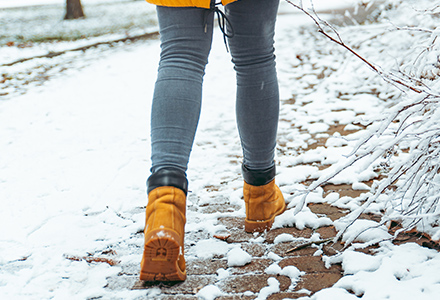 Woman wearing boots walking along snowy brick path