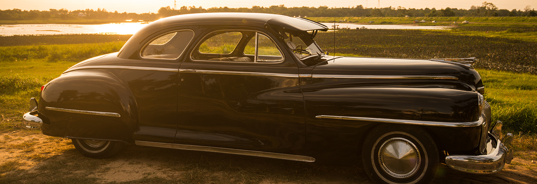 Vintage Automobile In Green Field At Dusk
