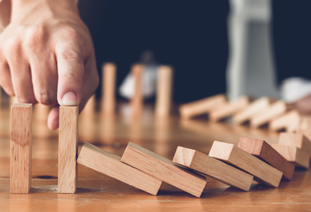 Man with finger on falling dominoes 