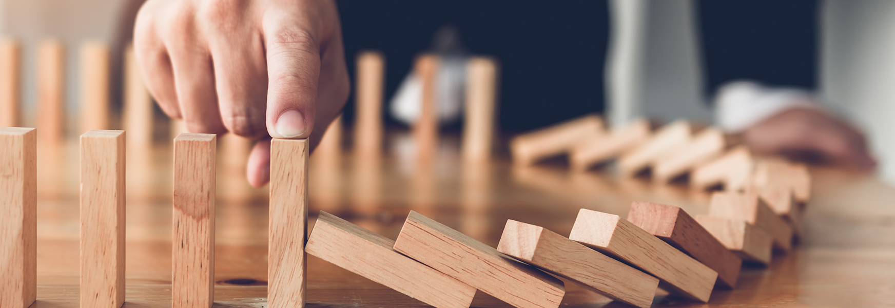 Man with finger on falling dominoes