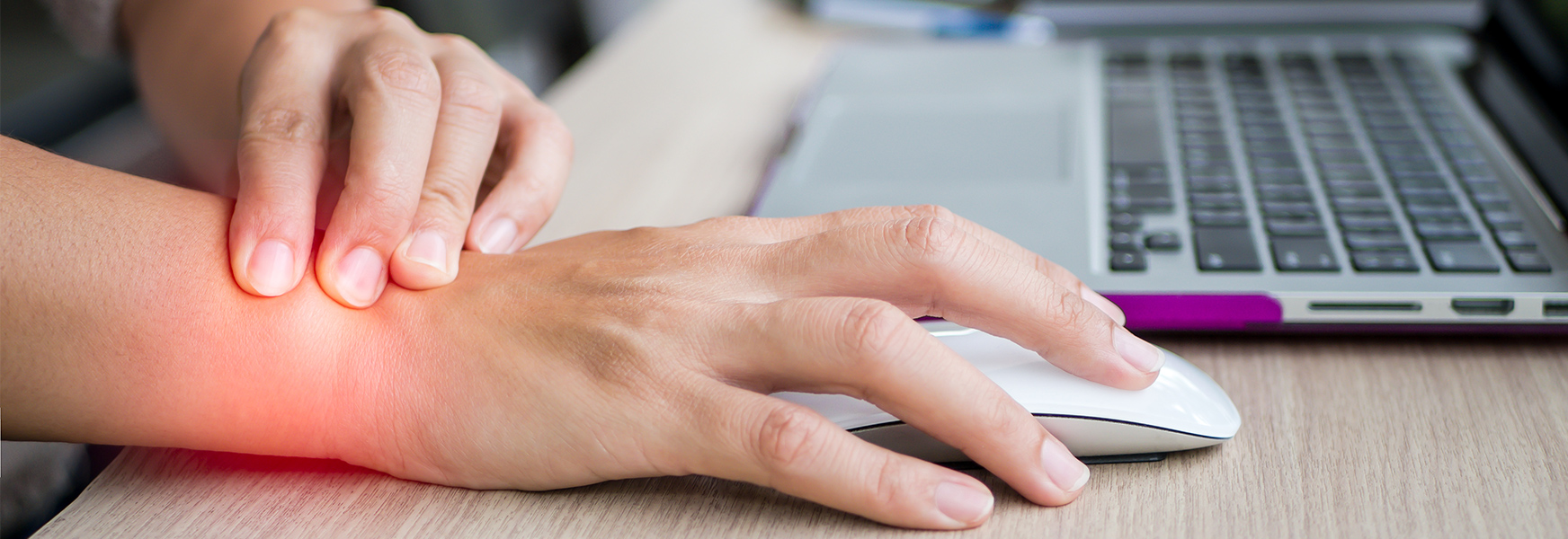 Woman using computer mouse grasping sore wrist