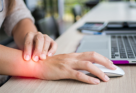 Woman using computer mouse grasping sore wrist