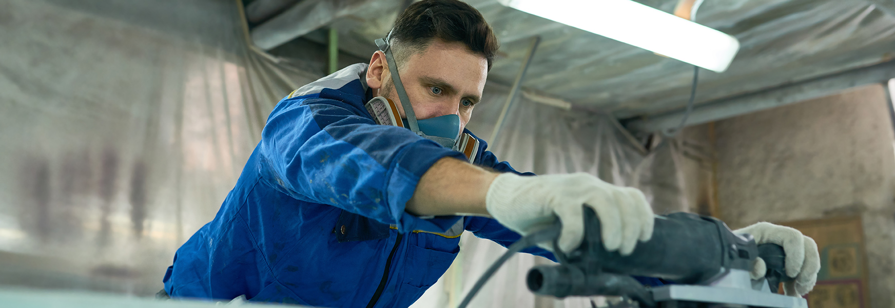 Man in respirator using a power sander