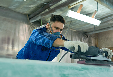 Man in respirator using a power sander