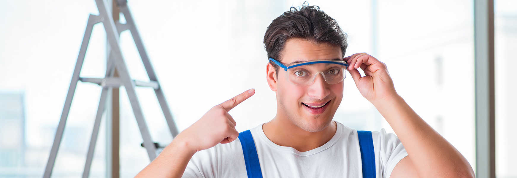 Young male worker pointing at safety glasses worn on his face