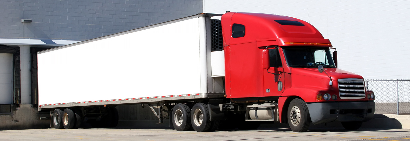 A semi truck sits parked at a loading dock