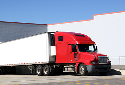 A semi truck sits parked at a loading dock