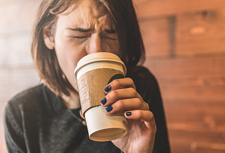 Woman sipping hot coffee and burning her mouth