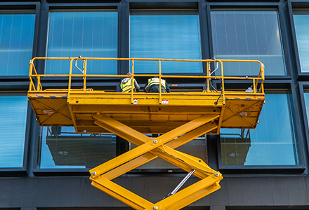 Workers in elevated work platform cleaning windows