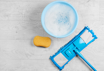 Microfiber mop with sponge and bucket on wooden floor