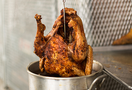 Deep fried turkey being removed from fryer.