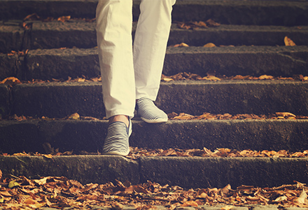 Legs walking down leaf-covered stone steps