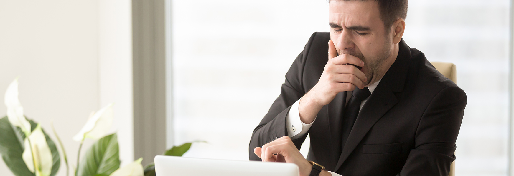 Office worker using computer and yawning at desk.