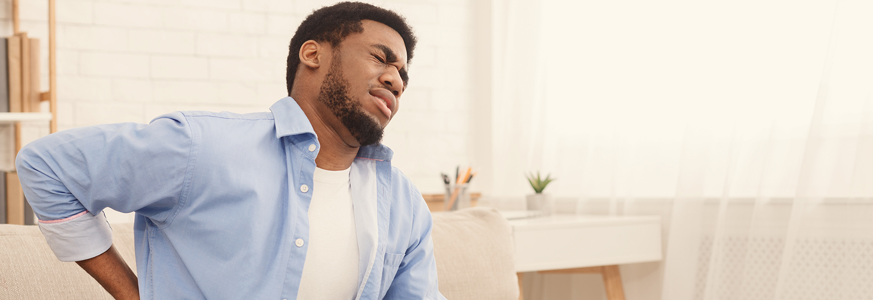 Man sitting on couch suffering from back pain