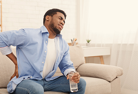 Man sitting on couch suffering from back pain