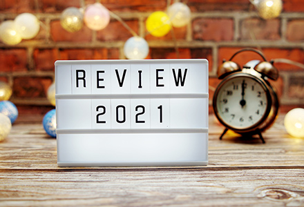 Marquee sign reading "Review 2021" on wooden tabletop against festive brick background