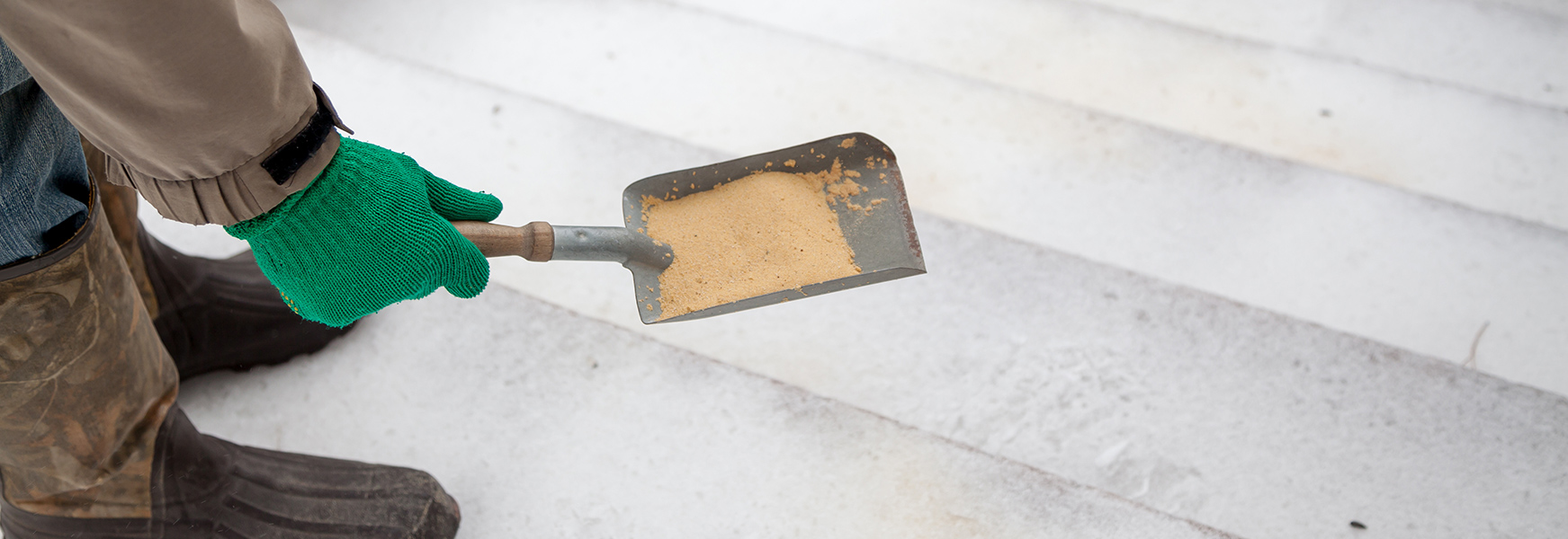 Person spreading dry sand on slippery steps