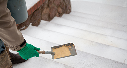 Person spreading dry sand on slippery steps