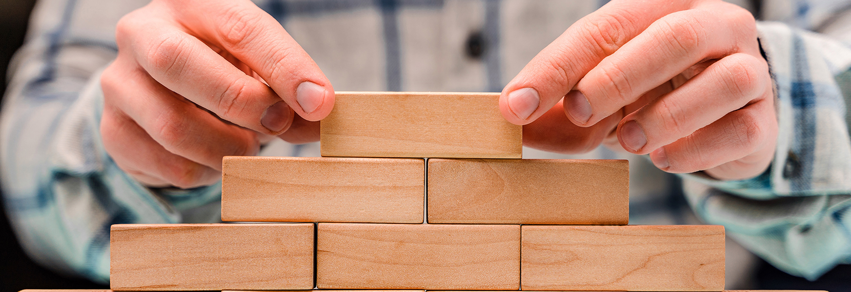 Hands stacking wooden blocks