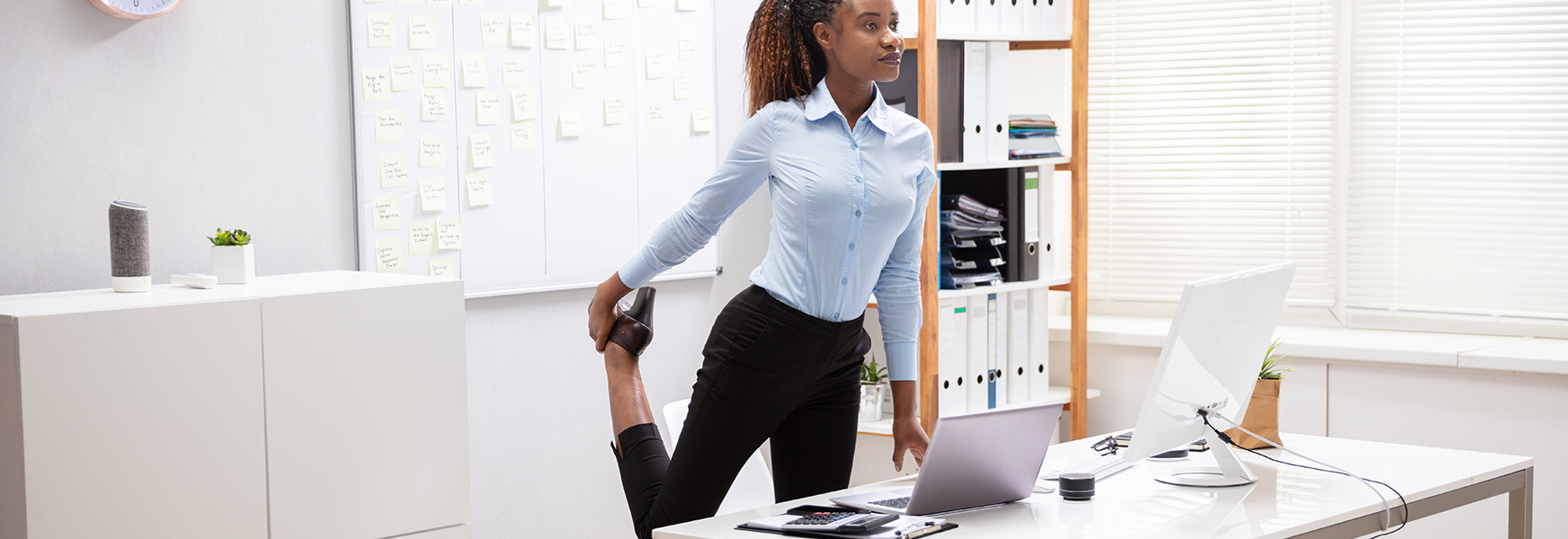 Young Businesswoman Doing Leg Stretches at Desk