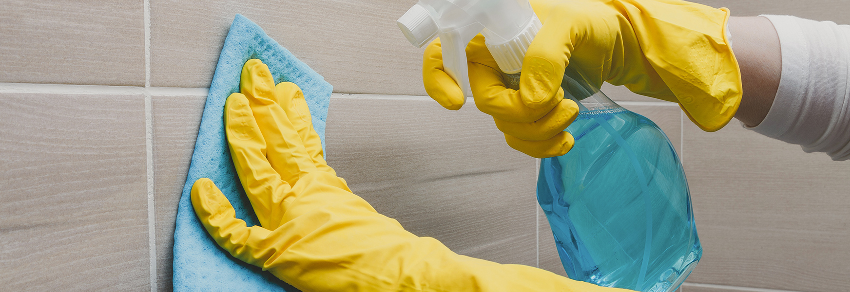 Gloved hands cleaning tile