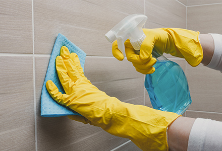 Gloved hands cleaning tile