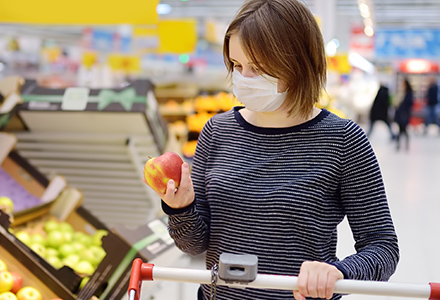 Young woman wearing a mask, shopping for fruit at a supermarket