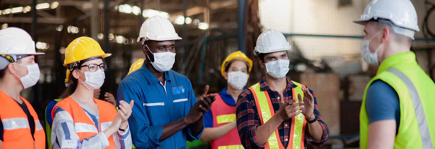 Masked factory workers having a standup meeting
