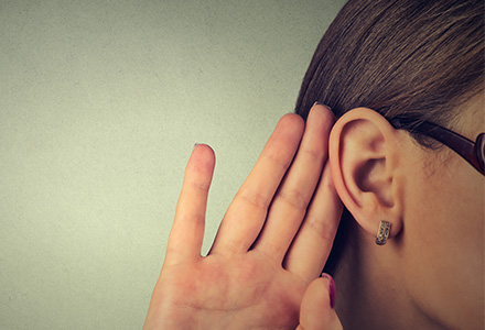 Woman holding hand to ear, trying to hear better