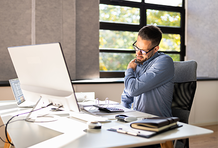 Man working at computer, struggling with back pain.