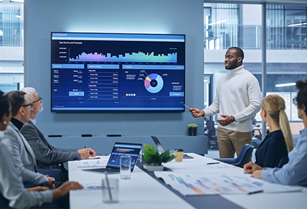 Man presenting data charts to office coworkers