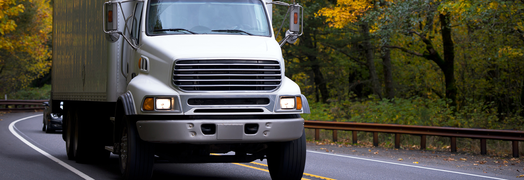 Box truck driving through wooded roads