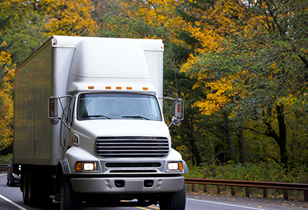 Box truck driving through wooded roads