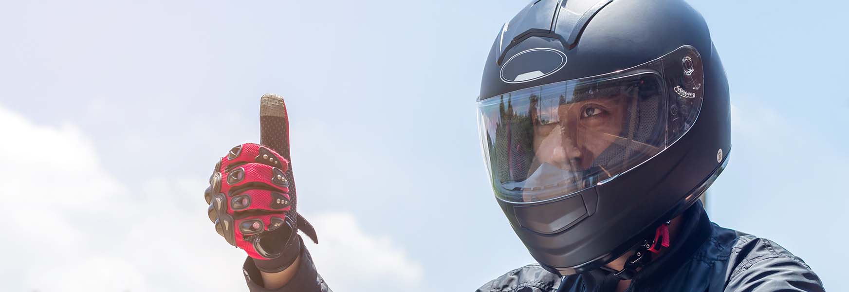 Motorcycle rider wearing helmet, giving thumbs up