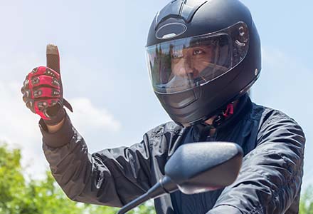 Motorcycle rider wearing helmet, giving thumbs up