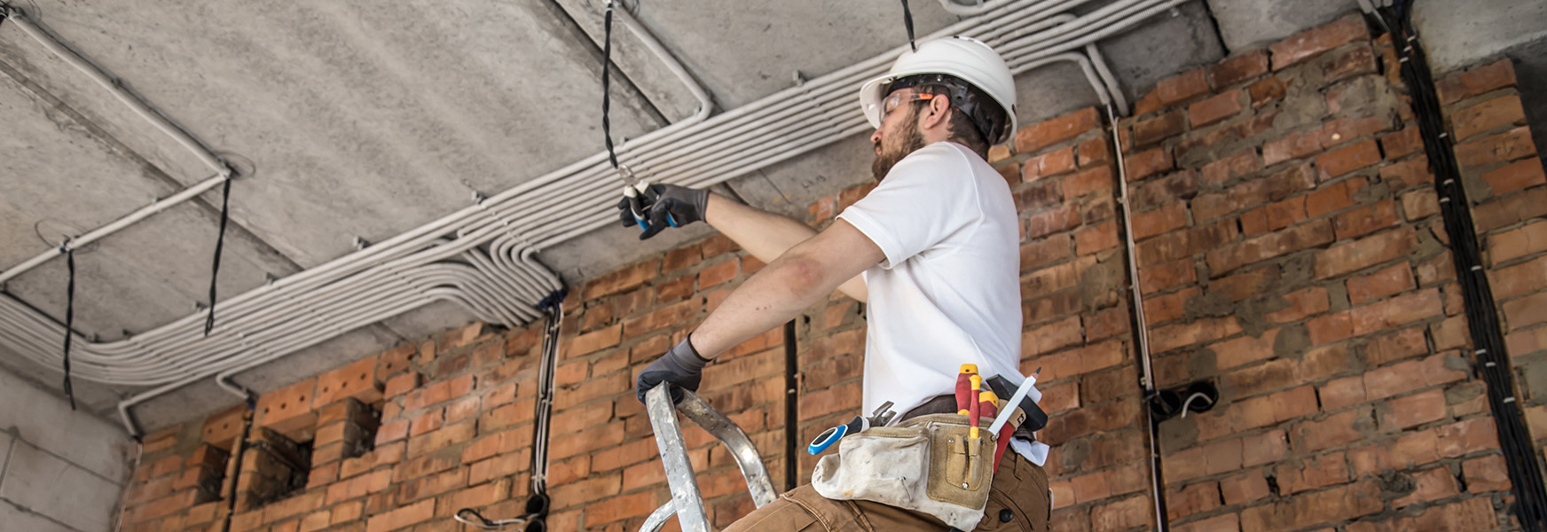 Man wearing PPE inspecting electrical outlet