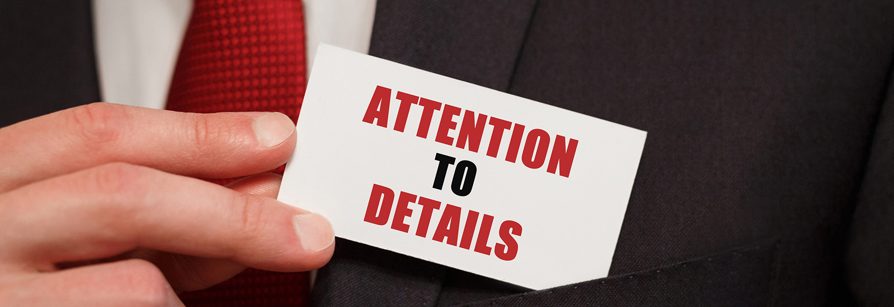 Business man holding business card that reads Attention to Detail