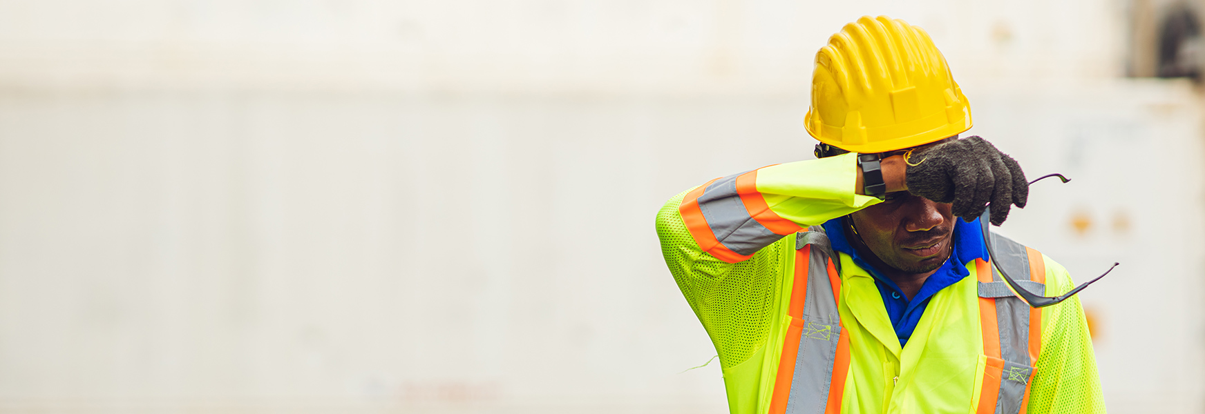 Construction worker wiping sweat from forehead during summer day