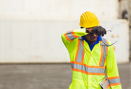 Construction worker wiping sweat from forehead during summer day