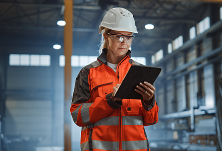 Safety professional wearing PPE and using tablet