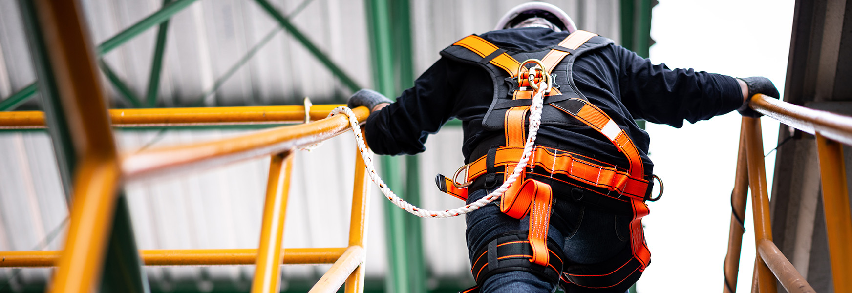 Worker climbing stairs with fall arrest harness attached