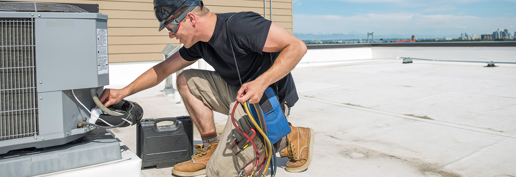 Worker inspecting HVAC unity on rooftop