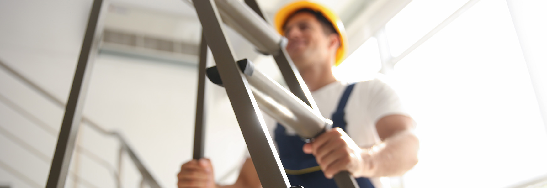 Worker wearing hardhat setting a ladder inside