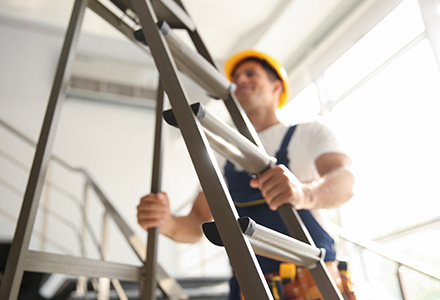Worker wearing hardhat setting a ladder inside