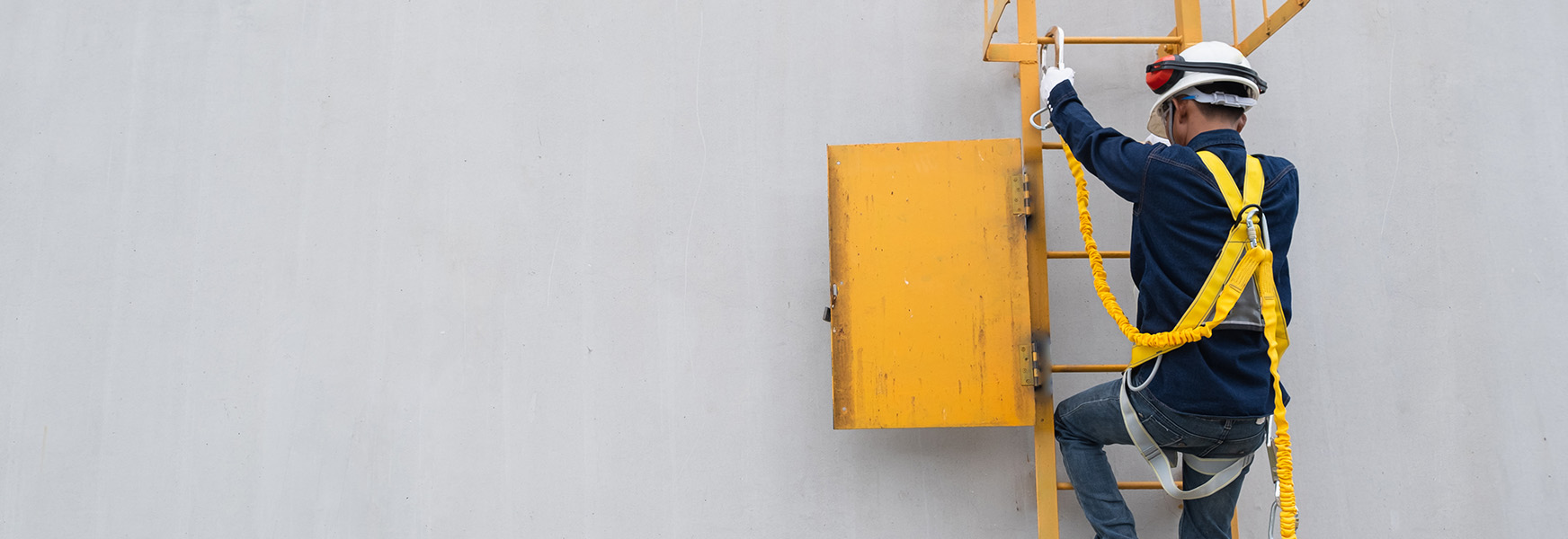 Worker wearing fall harness climbing a ladder