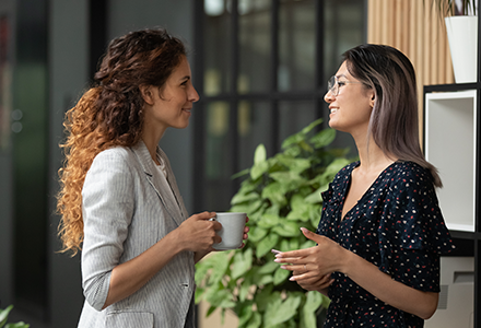 Women smiling and talking in office setting