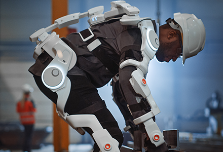 Man wearing exoskeleton suit lifting boxes